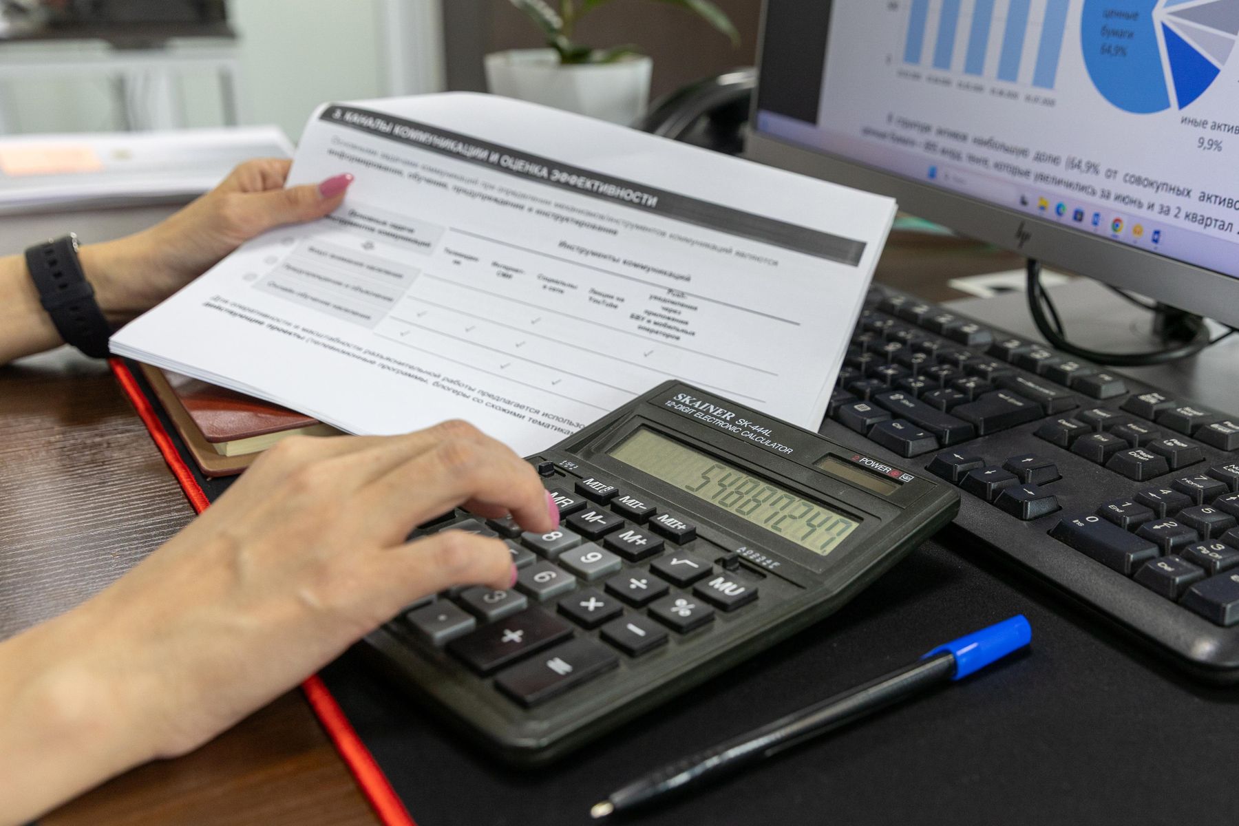 Person reviewing financial documents and calculations at a computer